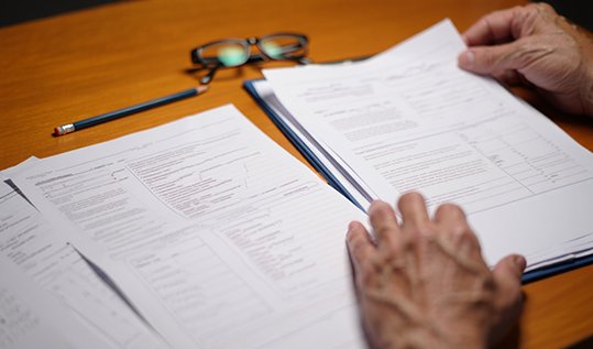 Крупный план рук психолога, проверяющего заполненные пациентом тесты и опросники