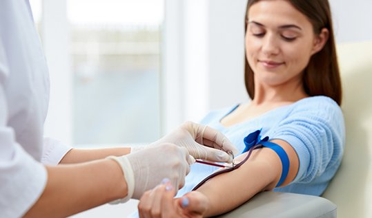 Медицинская сестра берет кровь из вены у пациентки в клинике